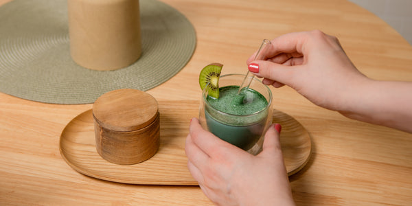 Une femme tient une boisson à base d'algues spirulines avec une paille