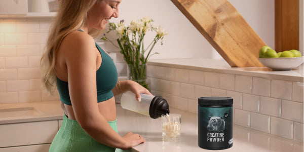 Une femme sportive avec un shaker et de la créatine nu3
