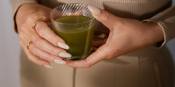 liquide vert dans un verre tenu à la main