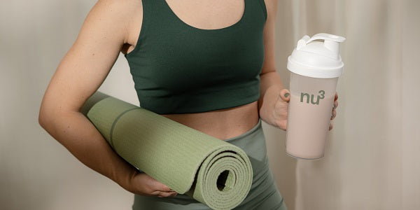 Une femme sportive avec un shake et un tapis