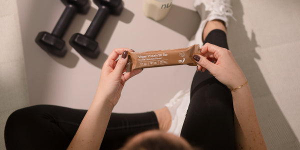 Une femme sportive avec une barre Vegan 3K à la main