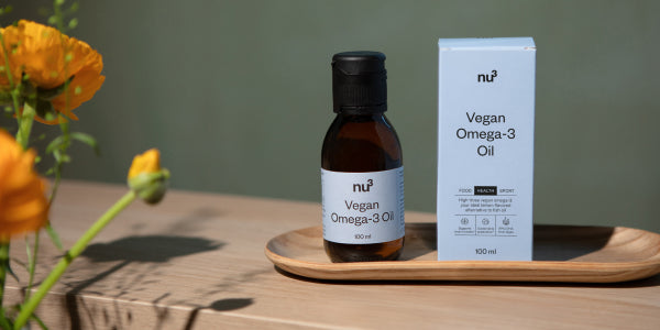 Flacons d'huile omega-3 vegan et emballage sur plateau en bois