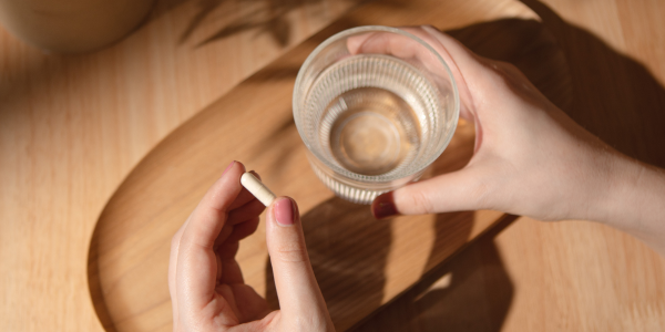 Main avec gélule de vitamine C & verre d'eau