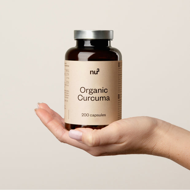 Main tenant un flacon de gélules de curcuma