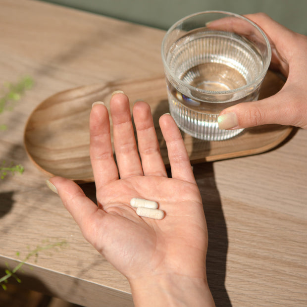 Gélules en main avec un verre d'eau