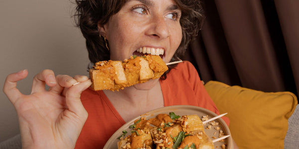 Femme mordant dans une brochette de tofu